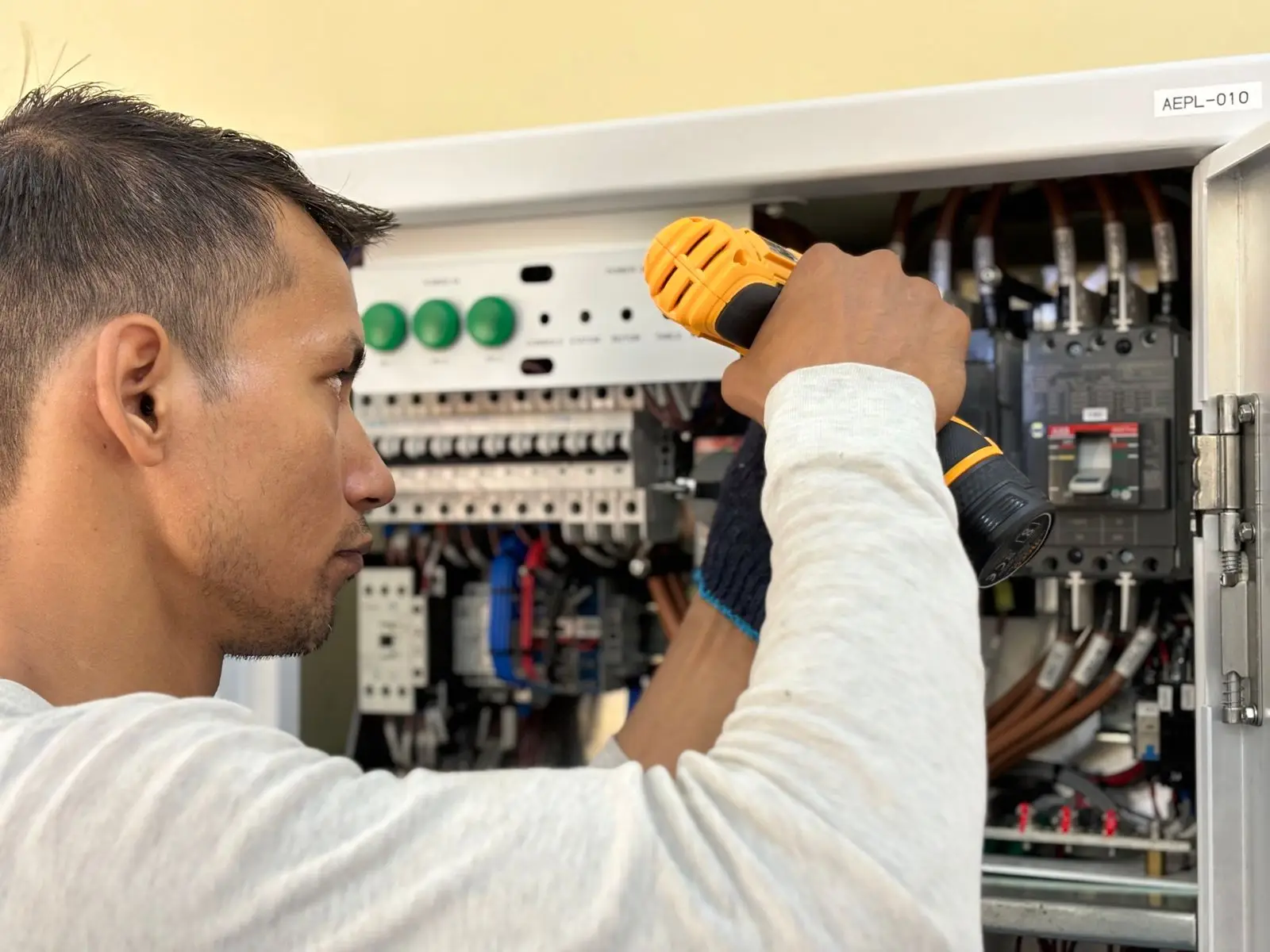 Electrician tightening a terminal on a row of breakers with a cordless driver