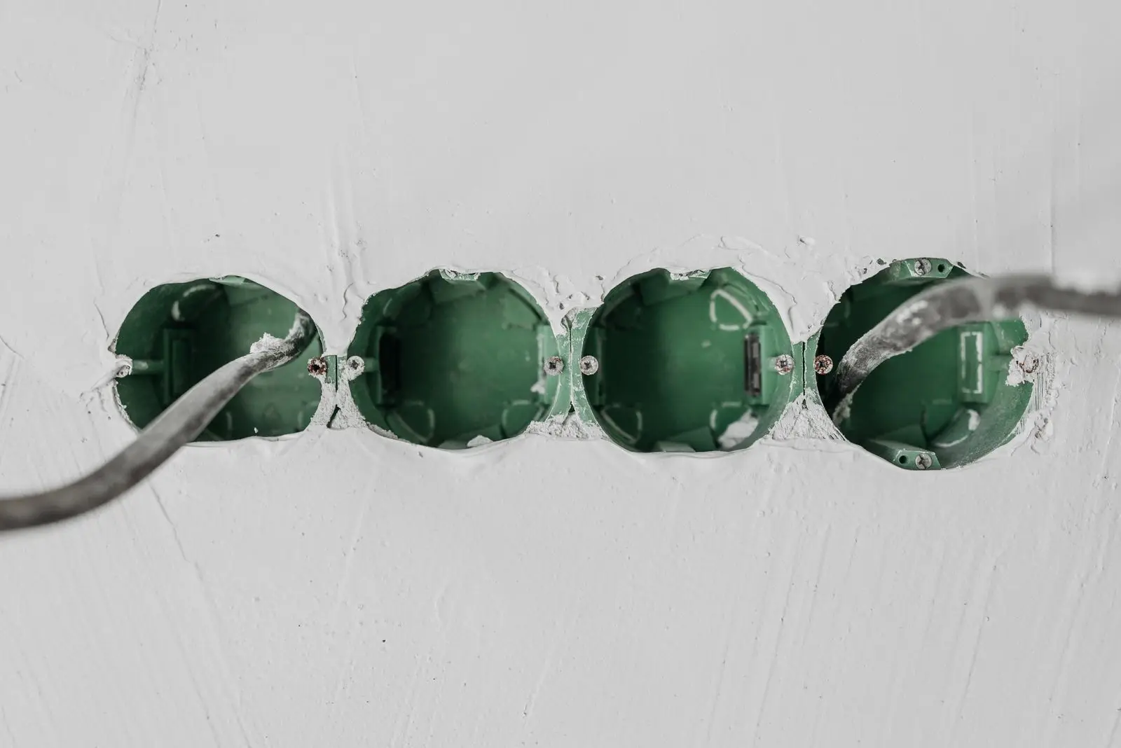 Row of empty wall boxes set into plaster with a cable entering from one side