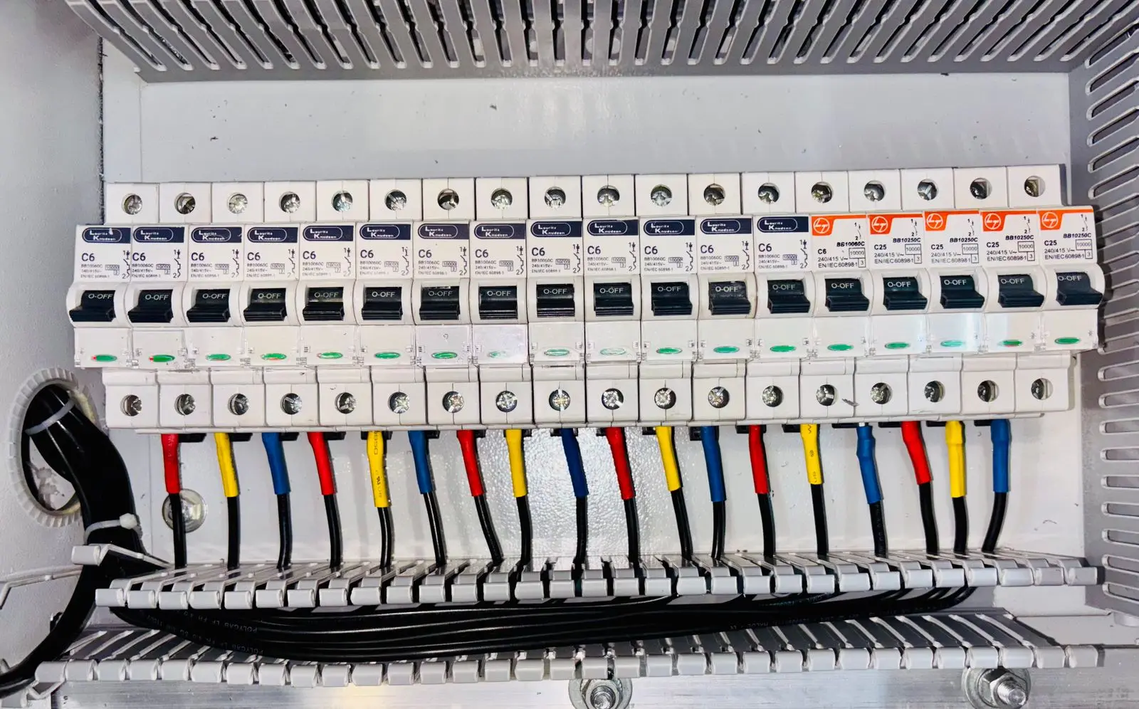 Long row of circuit breakers with colour-coded wires entering from below