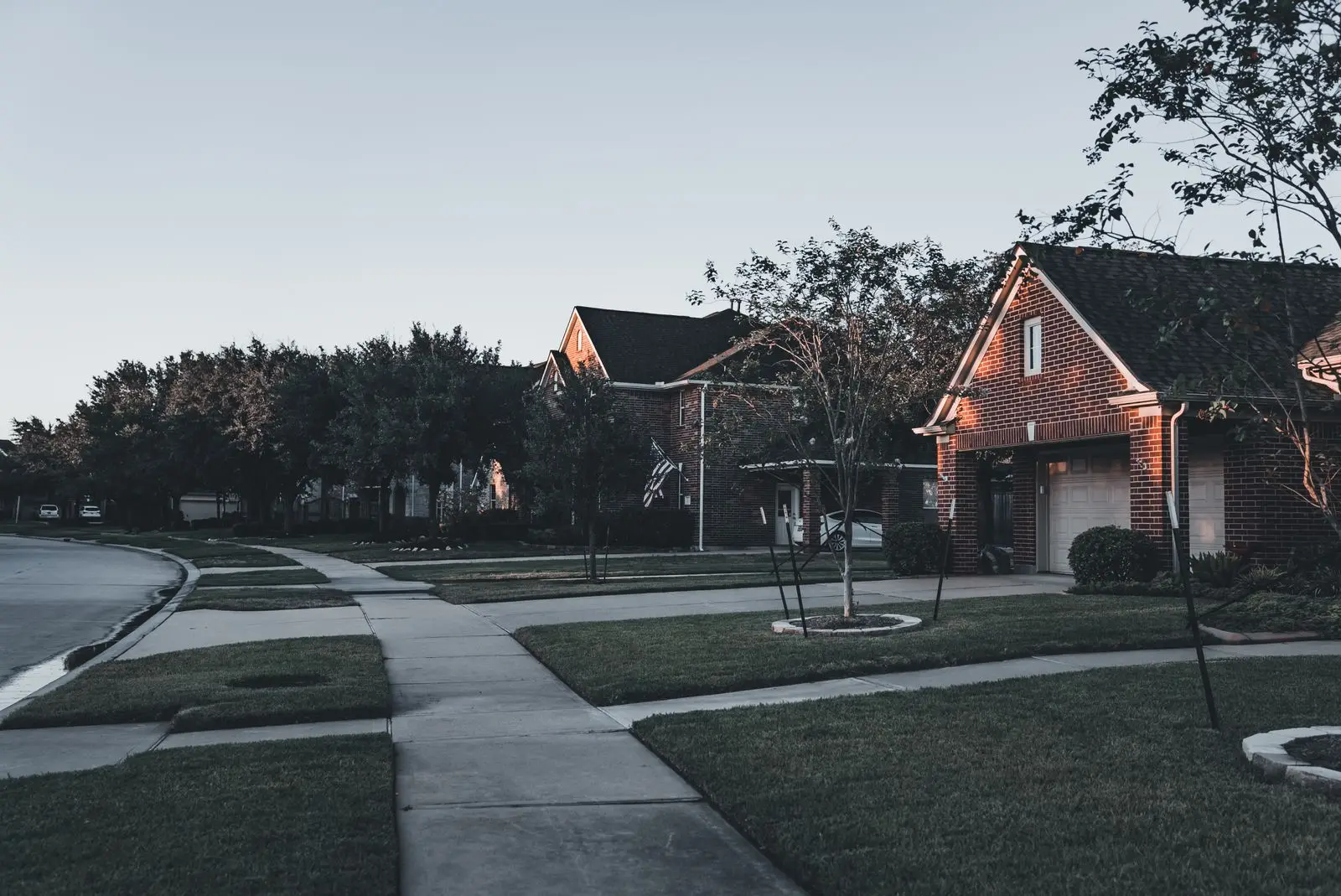 Suburban brick houses with driveways and lawns at dusk