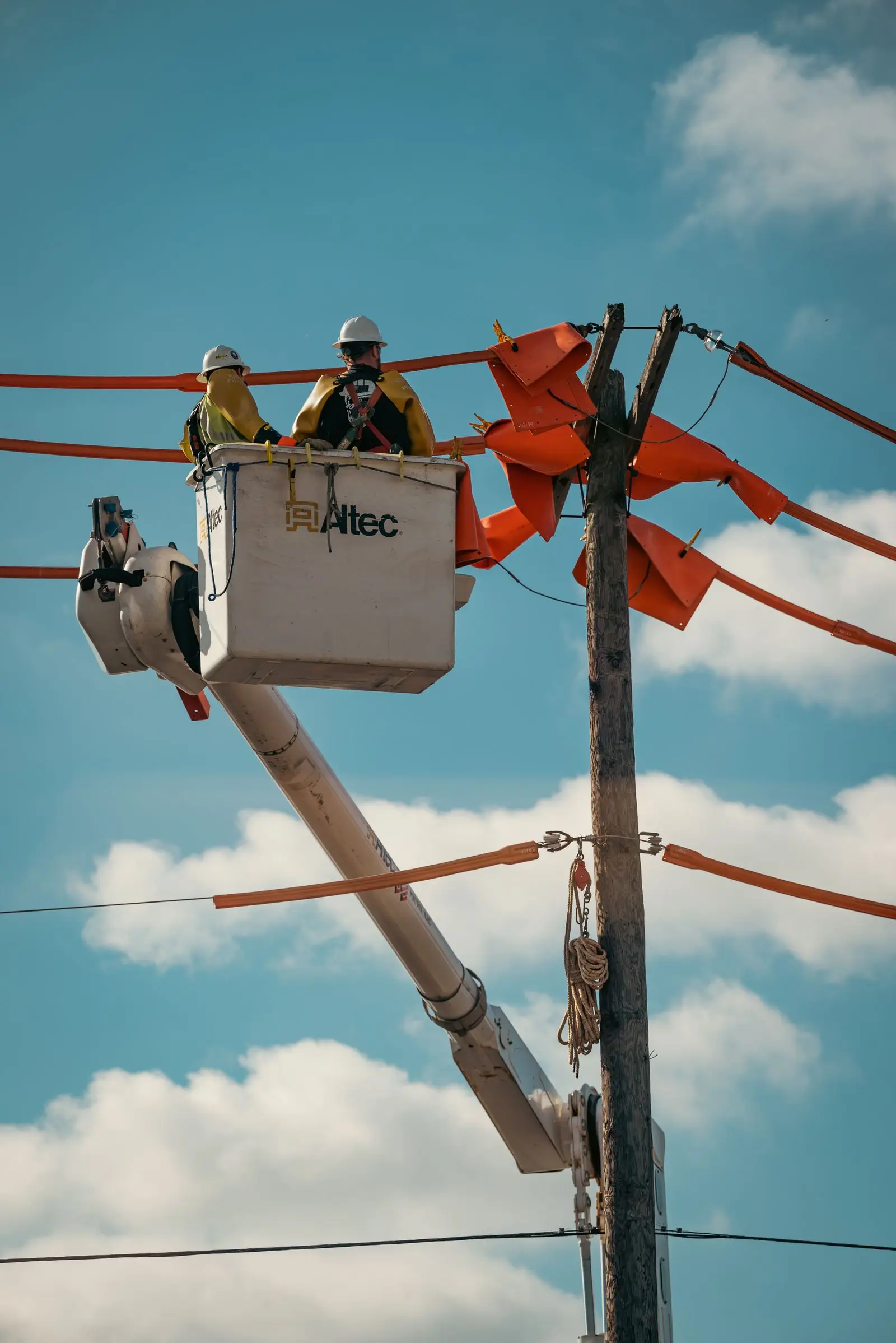 Line worker in a bucket truck beside a pole with covered conductors