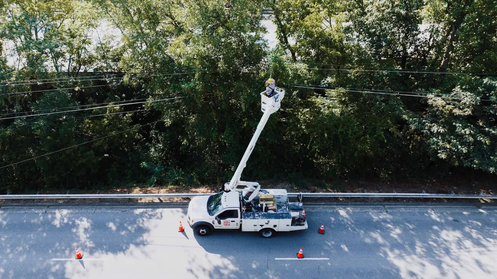 Aerial view of a utility bucket truck raised toward roadside lines
