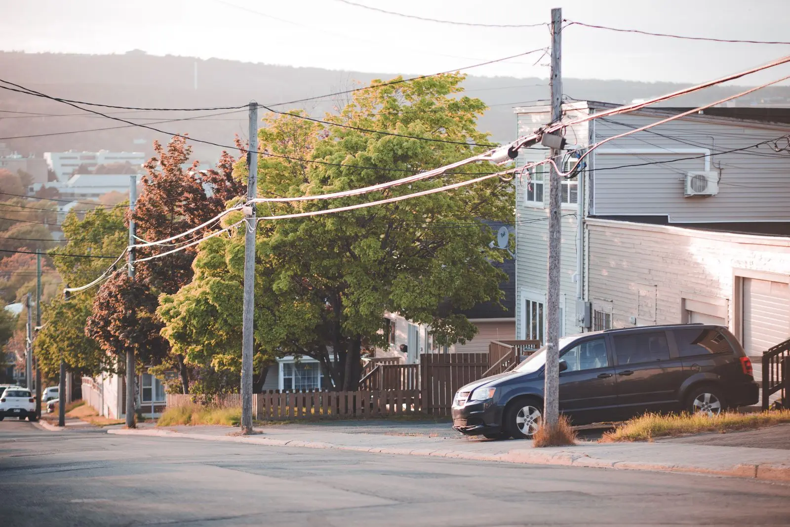 Utility pole with many attached lines on a suburban street corner