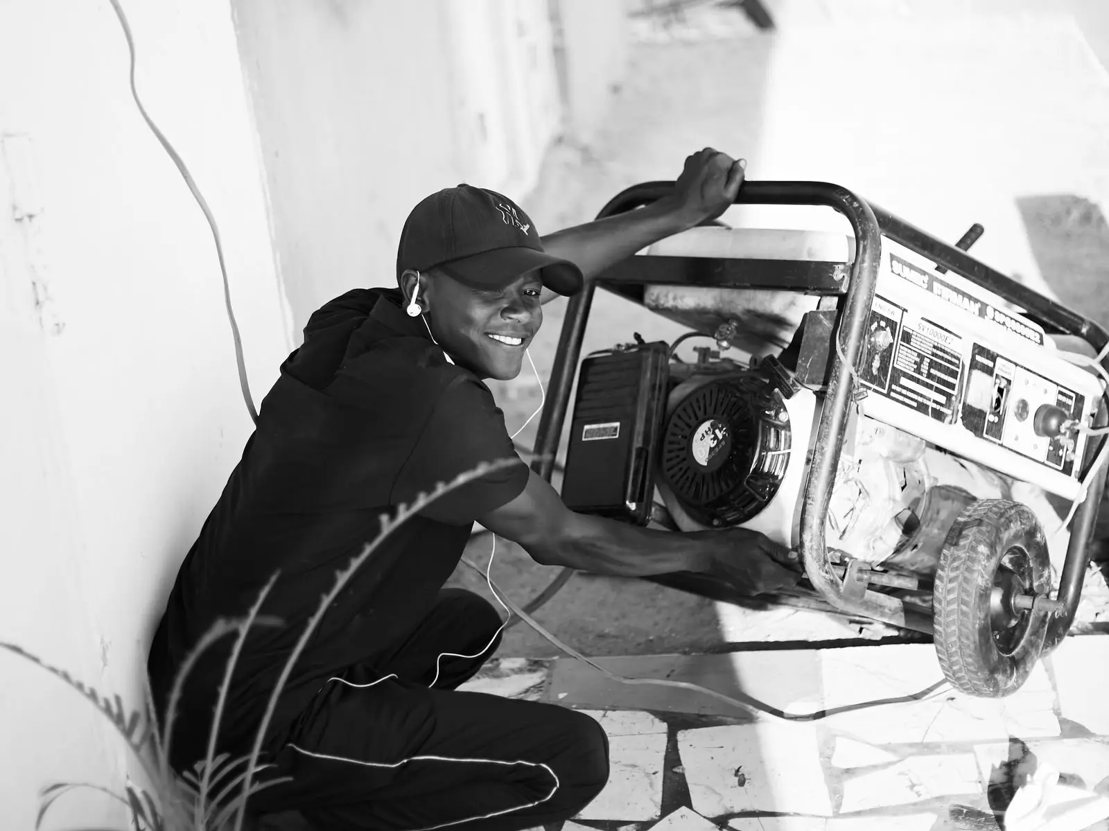 Black and white photo of a man beside an open-frame portable generator