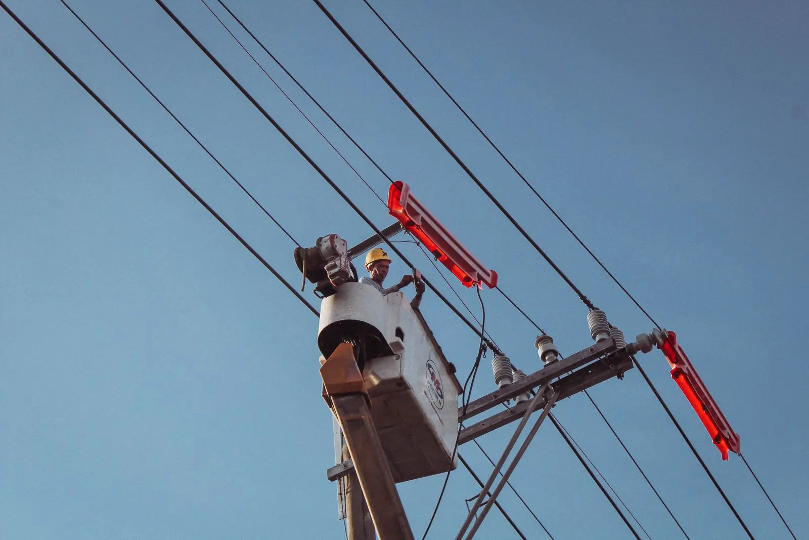 Line worker in a lift bucket working at a pole crossarm