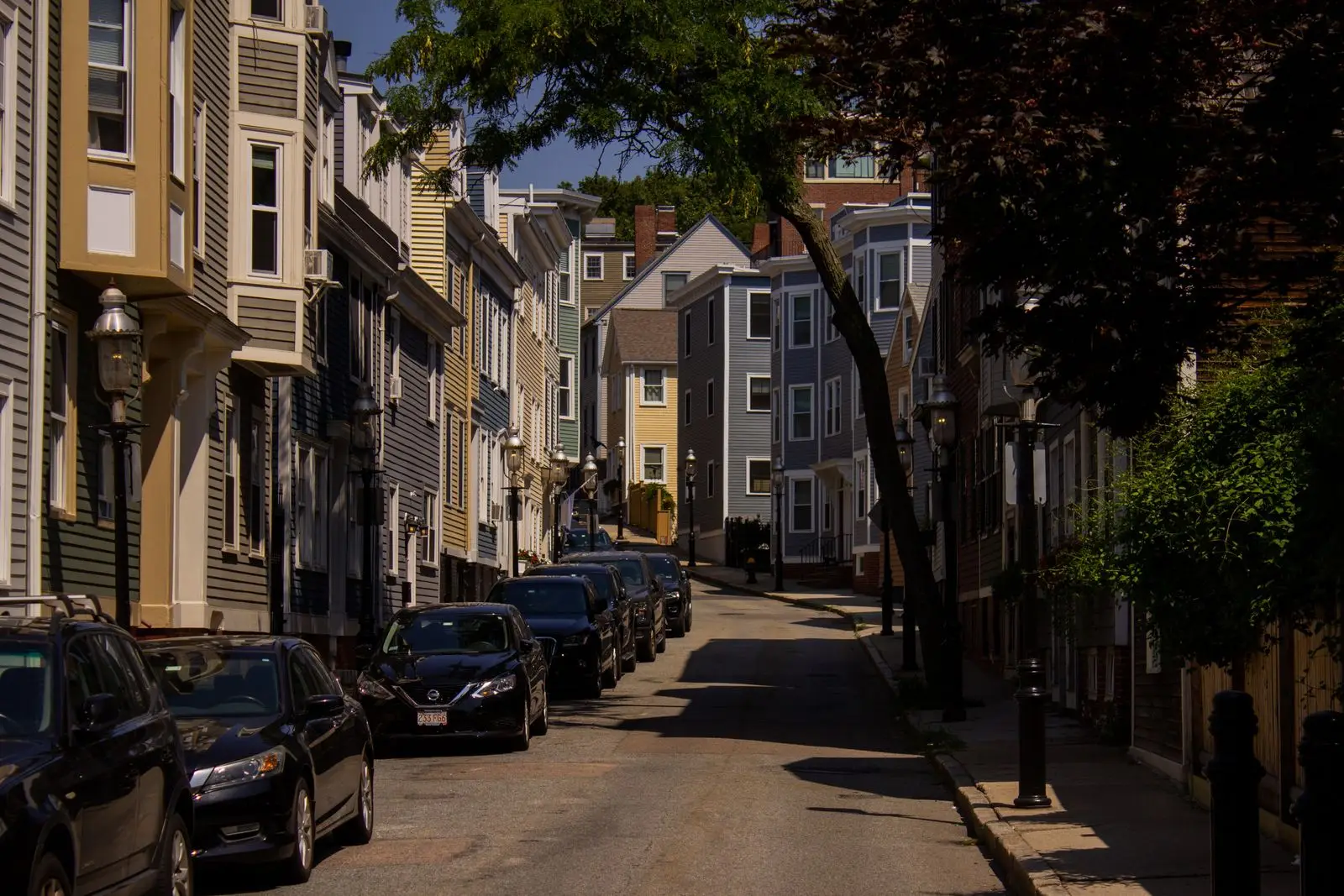 Narrow city street lined with old multi-story wooden rowhouses