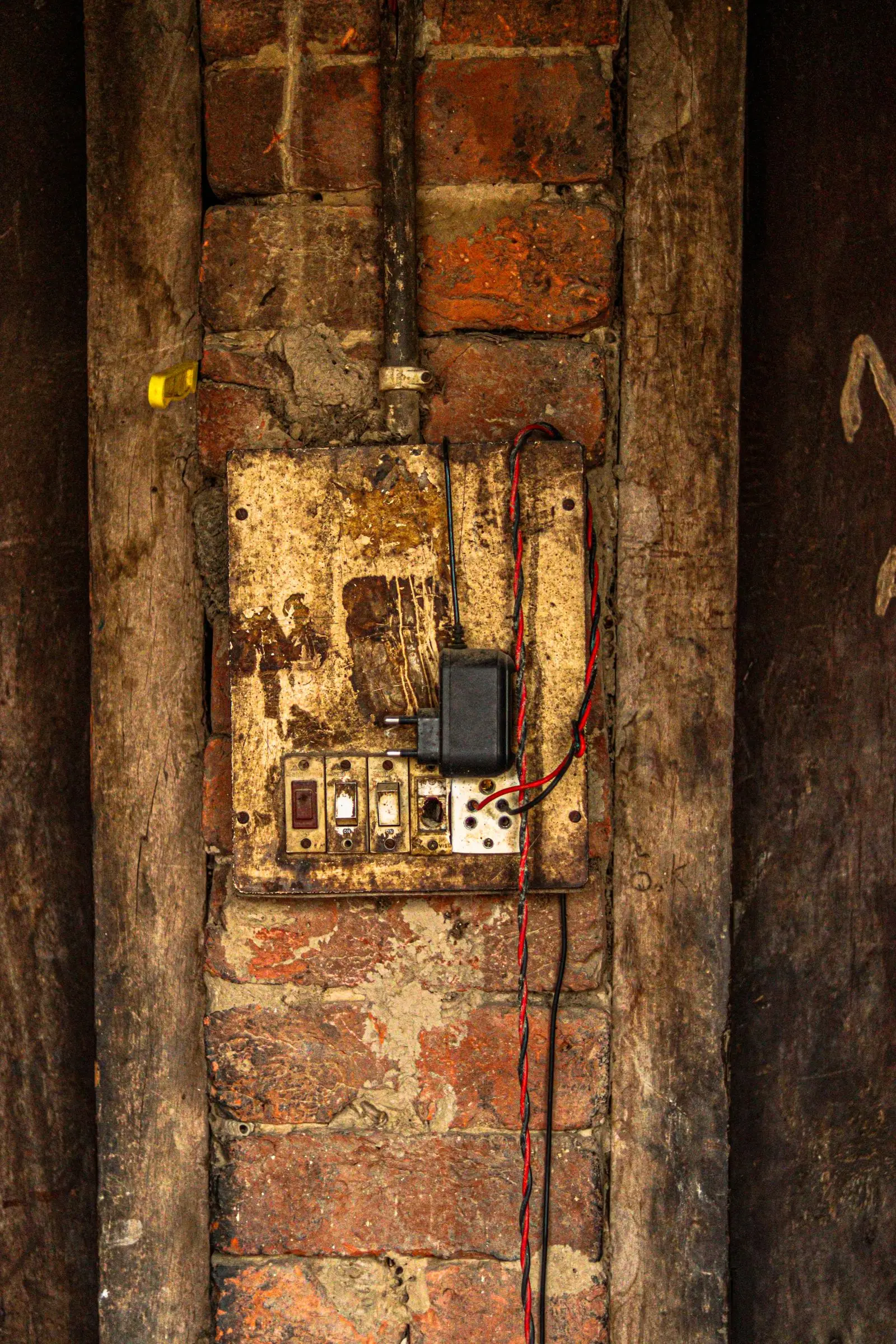 Corroded old fuse box fixed to a rough wooden wall