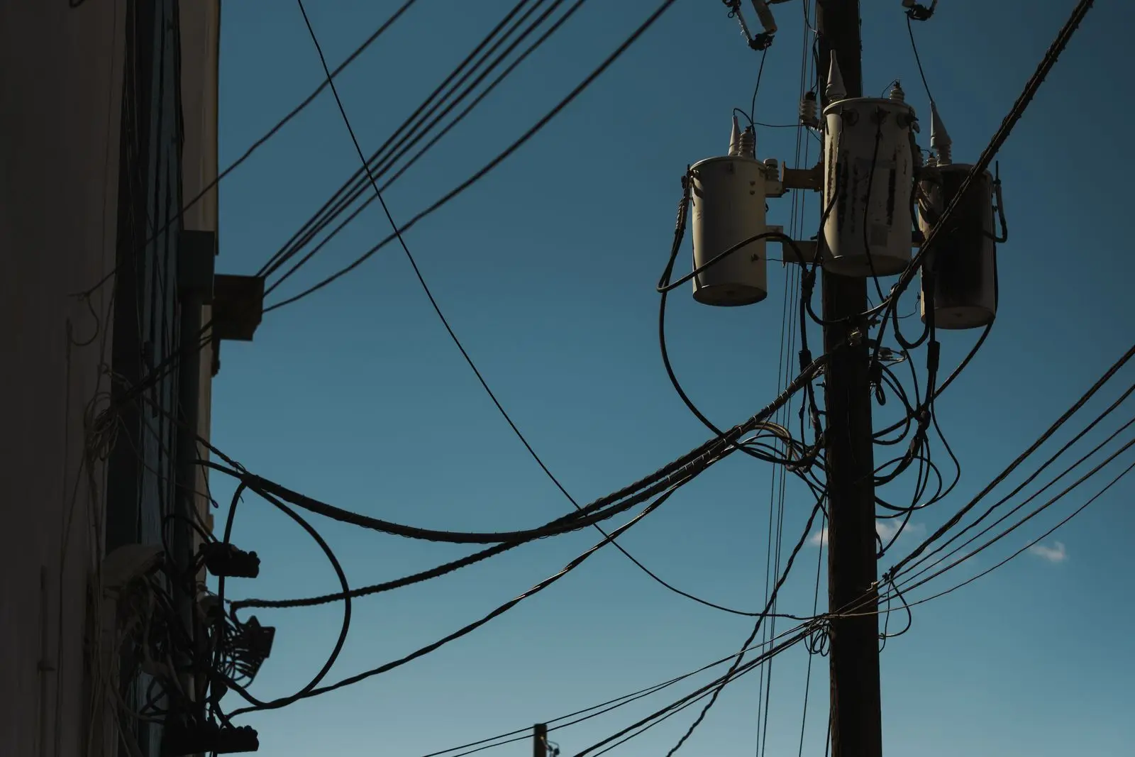 Pole-mounted transformers and service wires at dusk