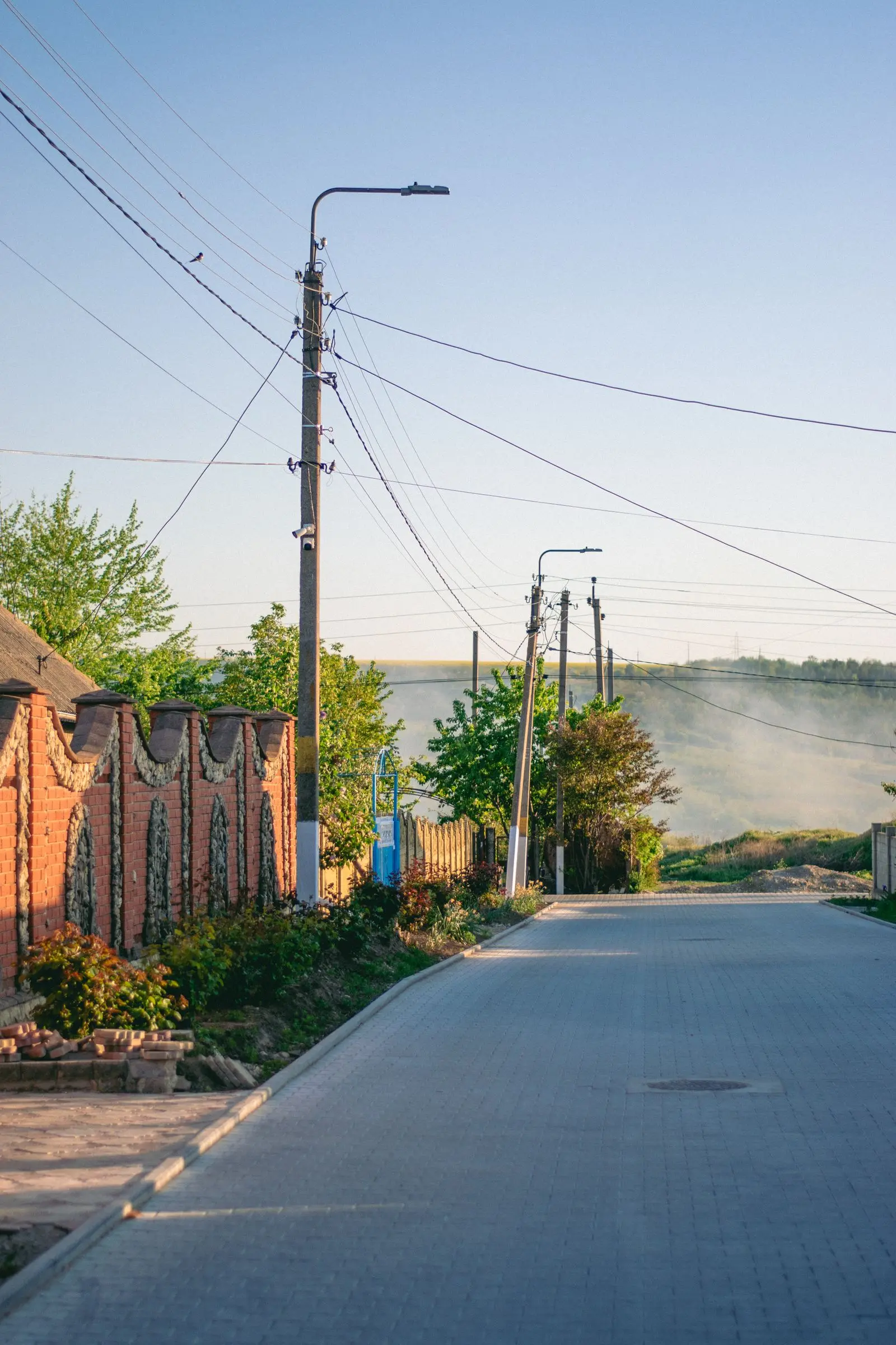Utility poles along a narrow street beside brick houses